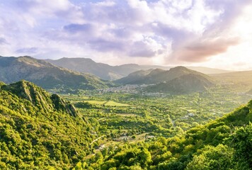 amazing highland view from above to a canyon and valley between mountains and green hills, cloudy sunset landscape of beautiful highland