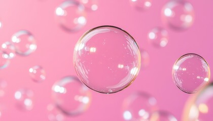Transparent soap bubbles gracefully float against a soft pink backdrop, creating a whimsical and serene atmosphere.