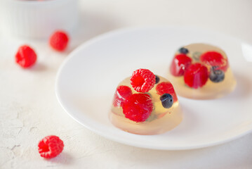 Natural jelly pudding with berries raspberries and blueberries on white plate. Homemade dessert.