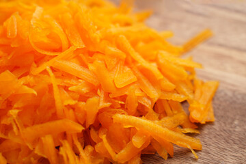 Peeled grated organic orange pumpkin pieces on wooden rustic board
