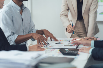 Business Meeting Analysis:  A group of diverse business professionals huddle around a conference table, intently reviewing financial data, charts, and graphs.