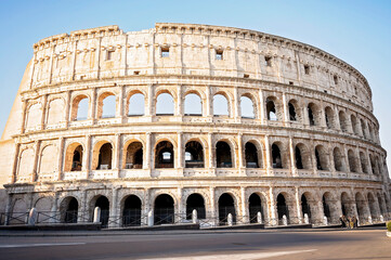 Fototapeta premium The Colosseum in Rome illuminated by warm sunlight against a clear sky