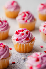 Small cupackes with pink frosting and hearts on white background.