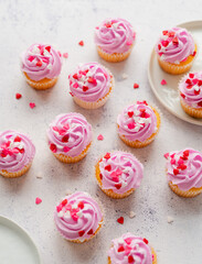 Small cupackes with pink frosting and hearts on white background.