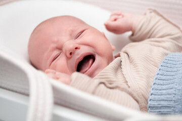 newborn baby cries loudly lying in cradle