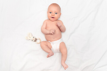 two month old baby smiling and looking at camera on light background, top view