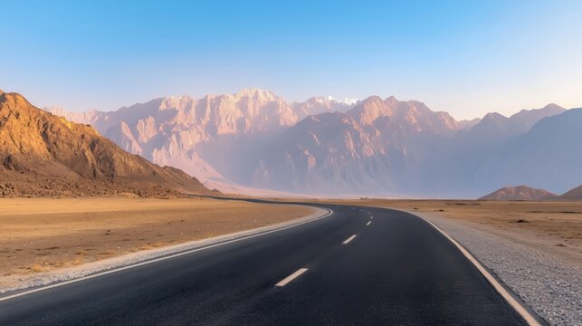 Winding road through arid landscape with distant mountain range in twilight