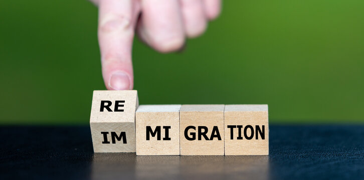 Hand turns cube and changes the word 'immigration' to 'Remigration'.