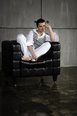 A young attractive man is sitting in a chair.