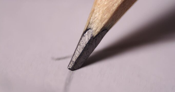 Close-up video of a pencil tip sketching fine graphite lines on textured paper. Captures intricate details of the drawing motion and wooden pencil material.
