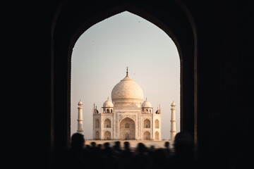 Taj Mahal Bei Sonnenaufgang in weichem, rosanen Licht umrahmt vom Eingangs Bogen durch die Besucher Menschenmassen ströhmen