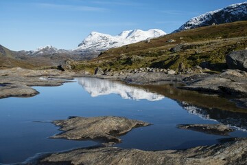 Fototapeta premium Okstindan mountain range, also Okstindene, with glacier Okstindbreen, water reflection in small mountain lake, Nordland, Norway, Europe