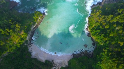 Drone view of coral hills on the edge of the sea with trees, coastal sand coral cliffs, and waves from the ocean at Sawangan Beach, Kebumen, Central Java