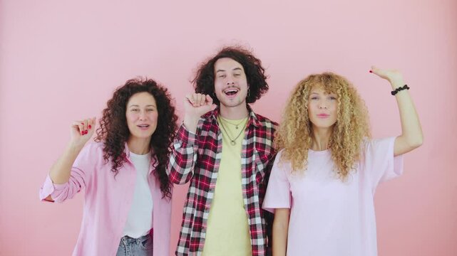 Three curly-haired friends waving goodbye and saying bye on a bright pink background with three cheerful people expressing their happiness and carefree spirit