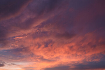 Dramatic sunset sky featuring deep purple and fiery orange clouds. Rich textures and fading light create a moody, serene, and captivating scene