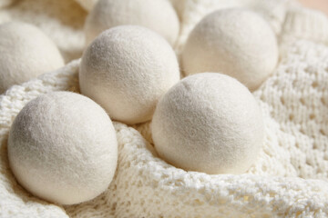 Soft wool dryer balls nestled on a textured white knitted fabric. Eco-friendly, reusable laundry alternative for static reduction and gentle drying