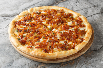Homemade delicious French onion pizza with gruyere and mozzarella cheese, thyme and garlic close-up on a wooden board on the table. Horizontal