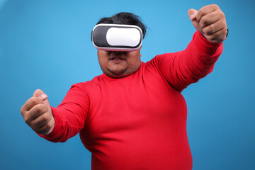 Naklejka premium Fat Man Wearing VR Glasses Gesture Driving A Car While Playing A Games Over Blue Studio Wall 