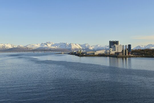 Industrial plant on blue Lang&oslash;ysund, behind the snowy peaks of Hinn&oslash;ya Stokmarknes, Nordland, Vesteralen, Norway, Europe