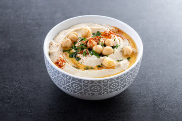 Chickpea hummus with olive oil, parsley and paprika on black background