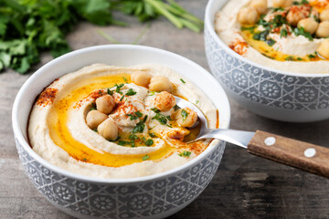 Chickpea hummus with olive oil, parsley and paprika on wooden table
