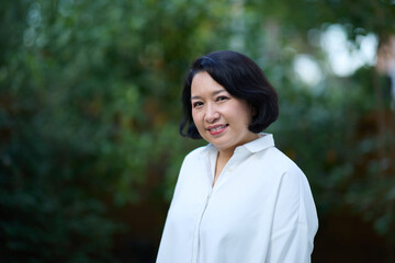Portrait of smiling middle aged Asian business women in natural background