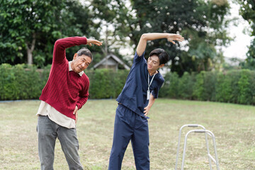 Obraz premium Health caregiver assisting elderly man with stretching exercises outdoors for rehabilitation therapy