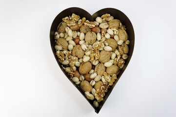 Various nuts, walnuts, hazelnuts, pistachios, in a heart shaped bowl