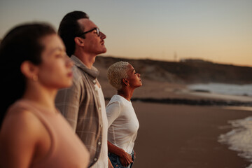 Friends enjoying golden hour on beach, breathing fresh air and relaxing