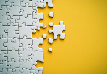 Fototapeta premium Sfondo giallo con pezzi di puzzle bianchi. Spazio per testo o messaggio.