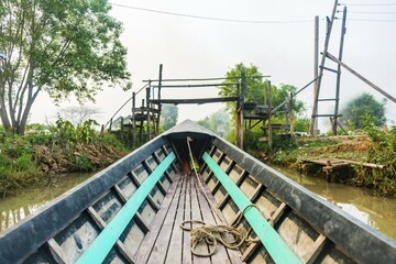 Wooden boat travels under wooden bridge on canal, Inle Lake, Shan State, Myanmar, Asia