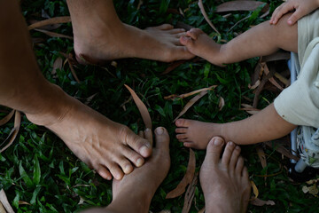 over head view of three pairs of feet family with baby on grass