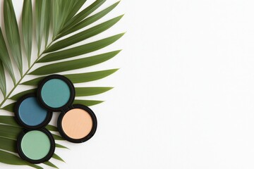 Stylish makeup powders beside a palm leaf on a clean background.