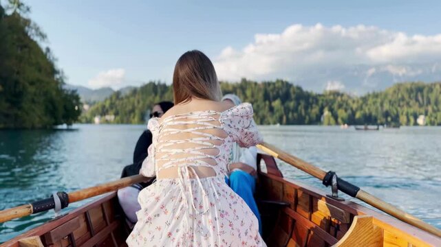 Girl rowing a boat back view beautiful female back beautiful backless dress, femininity, turquoise water lake, feminine and sports
