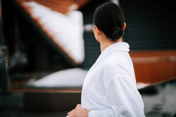 Fototapeta premium Woman in white robe enjoying winter holiday with snow-capped mountains in the background