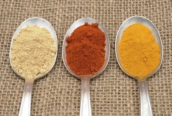Spices on an old spoon, ginger, paprika and curry powder