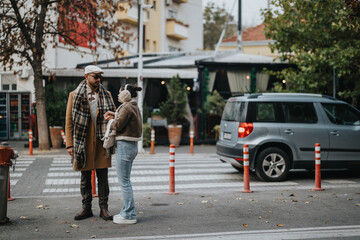 A stylish young couple having a conversation outdoors, dressed in fashionable winter outfits. Captured in an urban setting with a parked car and a background of greenery.