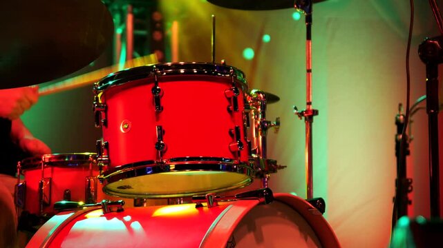 Close-up of the drummer's sticks playing on stage with a red drum set