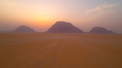 A serene view of the desert under a vibrant orange sky as the sun sets.
