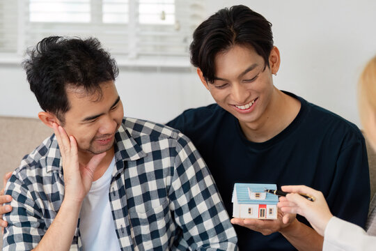 Diverse LGBTQ couple discussing home purchase with a model house.