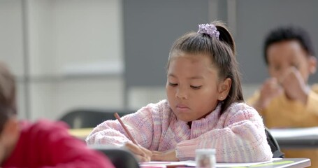 In school, girl writing in notebook in classroom, concentrating on lesson