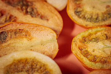 A detailed close-up of sun-dried tomato slices with rich texture and earthy tones arranged on a soft pink background, highlighting their natural and organic appearance.