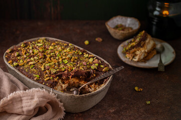 A piece of Dubai chocolate tiramisu with pistachio and chocolate ganache with candle. Italian tiramisu dessert with layers of lady finger biscuit and mascarpone. Professional food photography. 