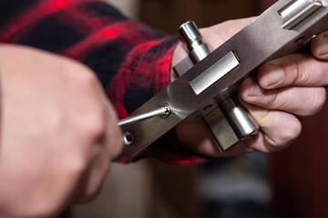 A male locksmith installs a new door lock on a metal door.