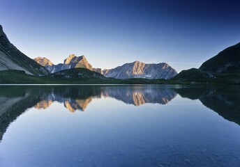 Mountains reflected in Lake Seewiessee near Memminger Huette alpine hut, Lechtal Alps, Tyrol,...