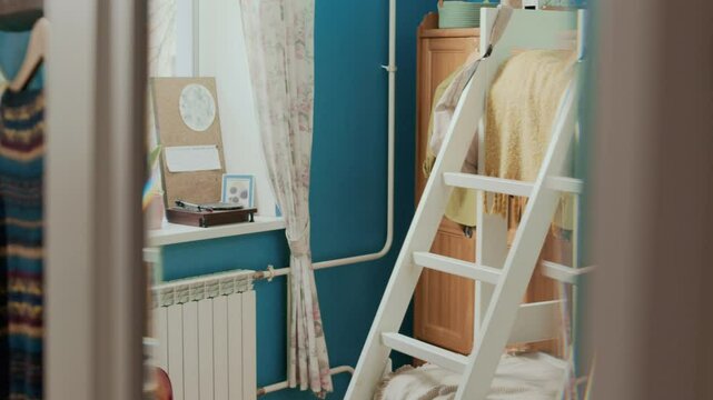 No people view through mirror of small students room with wooden bunk bed, wardrobe, stuff on windowsill and acoustic guitar by white heater