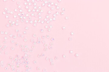 Iridescent acrylic beads scattered on a pink background with copy space.