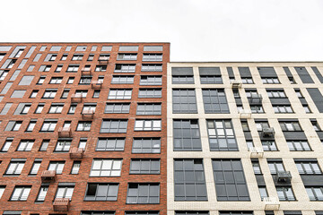 Contemporary multi-story buildings with beige, red brick and glass facades, balconies and windows....