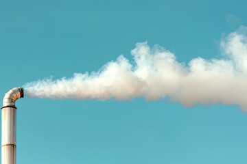 factory chimney releasing white smoke into clear blue sky, symbolizing industrial activity and environmental impact
