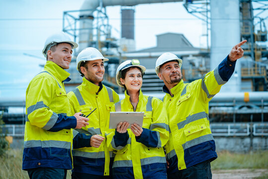 Team of workers discussing project details at industrial site during daylight hours - Powered by Adobe